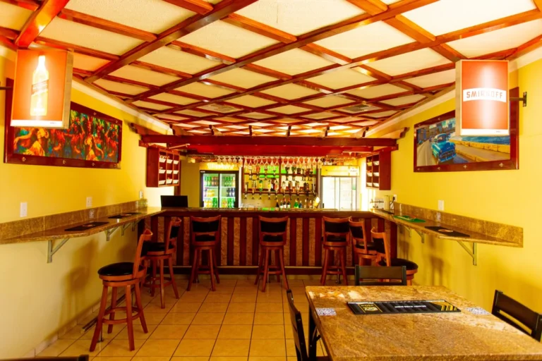 Indoor bar at Cubita Guesthouse with granite bar, wooden stools and drinks shelf.