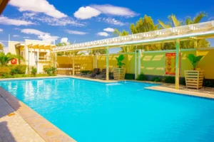Outdoor pool at Cubita Guesthouse with pergola, sun loungers and tropical plants.
