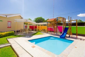 Children's recreation area at Cubita Guesthouse with swimming pool, wooden games, slide and bright colors.