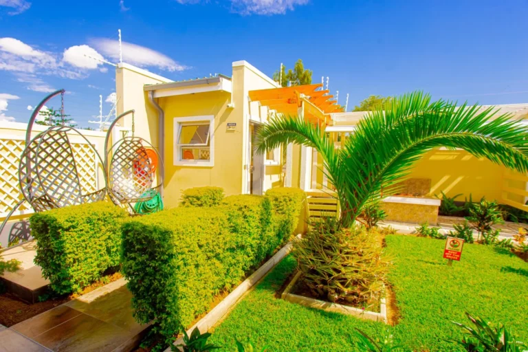 Outdoor area next to the rooms at Cubita Guesthouse with tropical garden, pergola and hanging chairs.